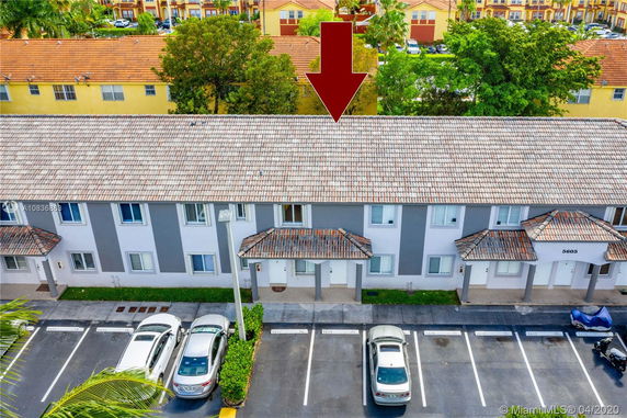 Front view of a residential building with a parking area in front.