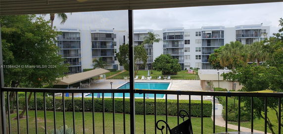 View of apartment buildings with balconies overlooking a pool area and greenery.
