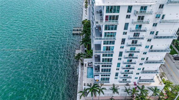 Exterior view of a modern high-rise building with balconies overlooking the water.