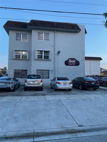 Front view of a three-story building with a parking area in front.