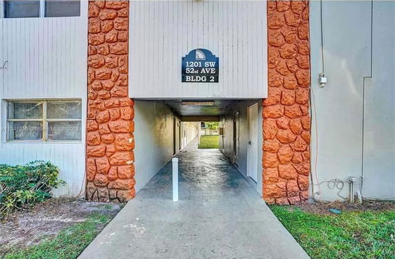 Front view of a building with an entrance pathway and visible stone facade.
