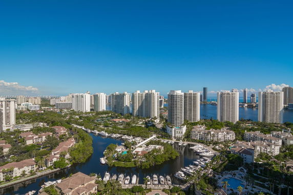 Panoramic view of high-rise buildings with a marina and waterway in the foreground.