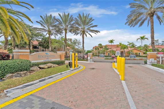 Entrance view of Edgewater Condominiums with gated access and surrounding palm trees.