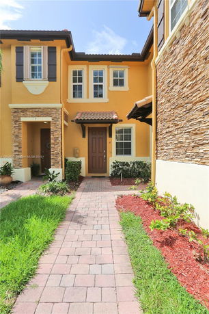 Front view of a two-story house with a brown door and decorative stone accents.