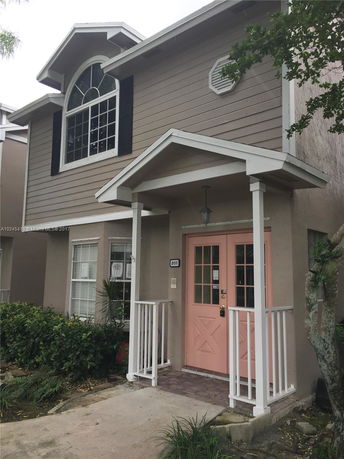 Front view of a two-story house with a pink front door and large window above.