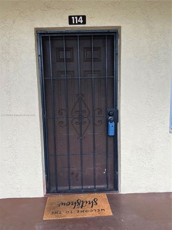 Front view of a building entrance with a metal security door and number 114 above.