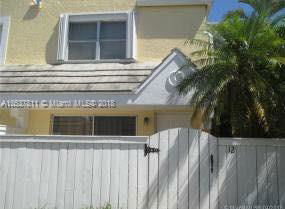 Front view of a house with yellow walls and white fence.