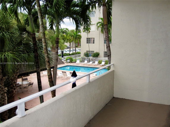 View from a balcony overlooking a swimming pool and surrounding buildings.