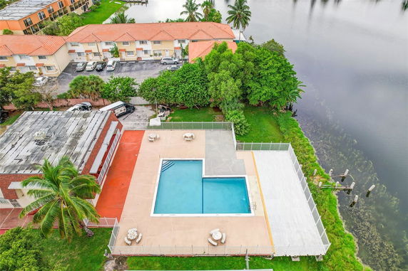 Aerial view of a swimming pool with adjacent patio area in a residential complex.