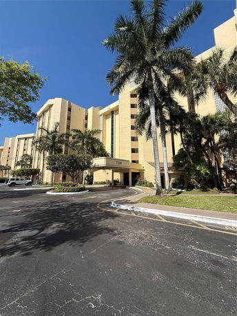 Front view of a multi-story building with palm trees.