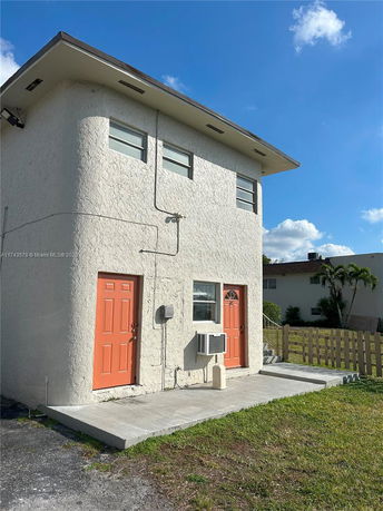 Front view of a two-story building with textured walls and orange doors.