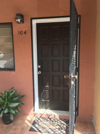 Front view of a house entrance with a brown door and a welcome mat.