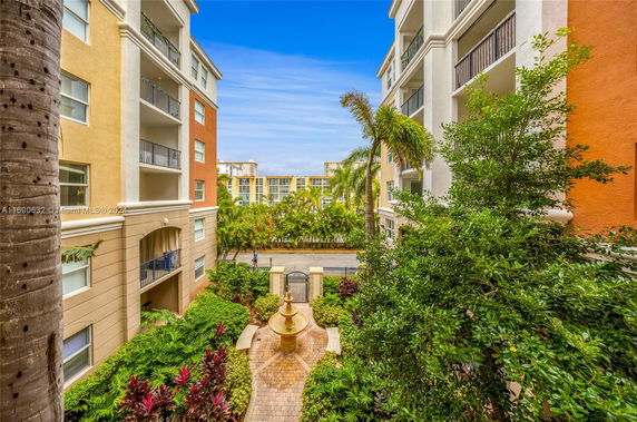 View between apartment buildings with a central landscaped area and a distant building visible.
