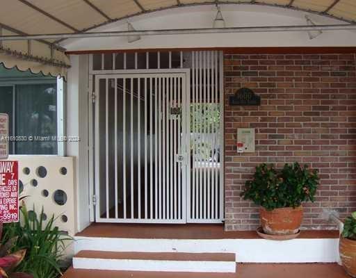 Front view of a building entrance with a gated door and brick wall.