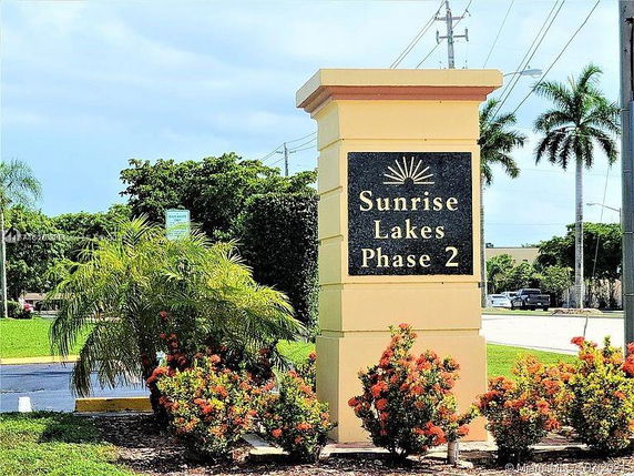 Sign for Sunrise Lakes Phase 2 surrounded by plants and trees.