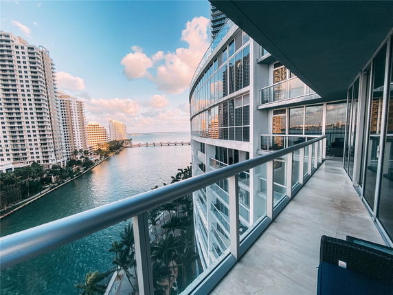 View from a high-rise building balcony showing nearby skyscrapers and a waterway.