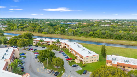 Aerial view of residential buildings with a parking area and a river in the background.