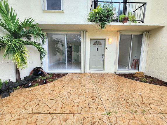 Front view of a two-story house with sliding glass doors and a balcony with plants.