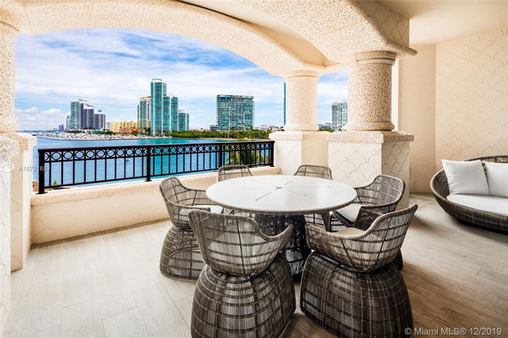 Balcony with a round table and chairs overlooking the water and city skyline.