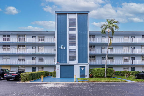 Front view of a multi-story residential building with balconies and blue accents.