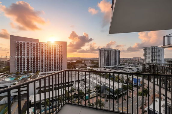 Panoramic view from a balcony showing high-rise buildings and cityscape at sunset.