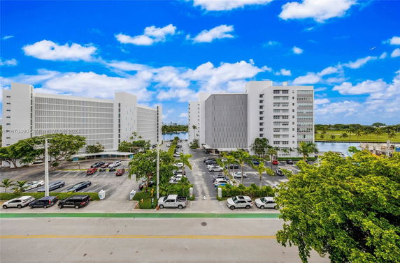 View of multiple multi-story buildings with parking areas and a waterfront nearby.