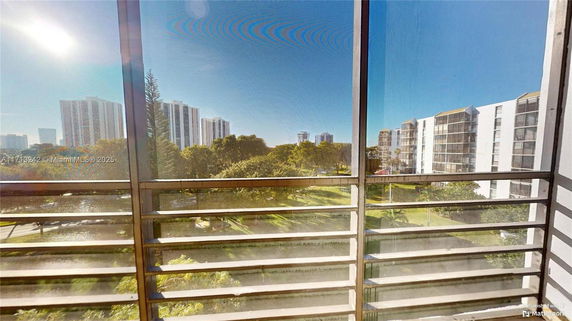 Panoramic view from a balcony overlooking surrounding high-rise buildings and greenery.