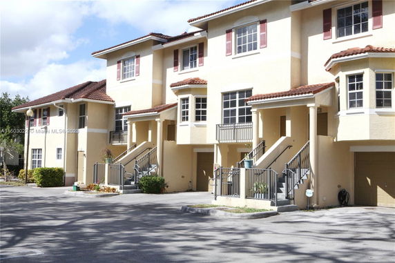Front view of a two-story building with a garage and stairs leading to the entrance.