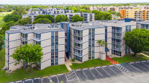 Front view of a multi-story residential building with balconies and parking area.