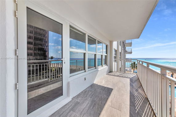 Balcony overlooking the ocean with a view of adjacent buildings and the beach.