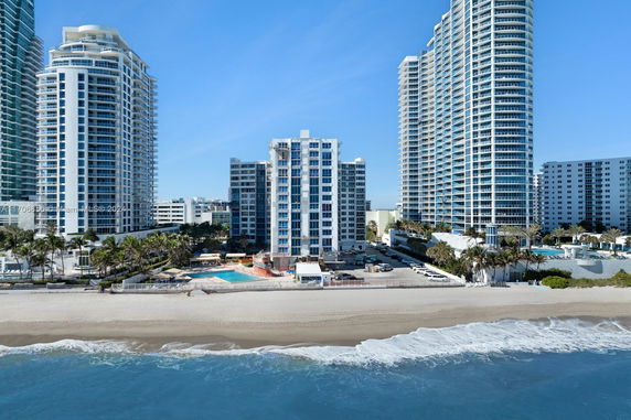 Beachfront view of tall residential buildings with balconies and glass windows.
