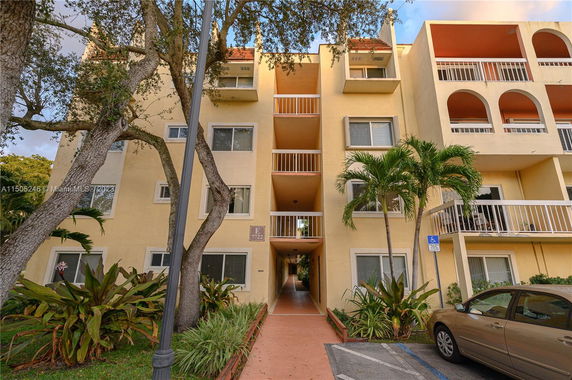 Front view of a multi-story residential building with balconies and a pathway entrance.