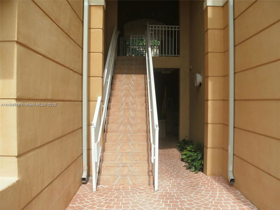 Exterior view of a building with stairs leading to an upper entrance.