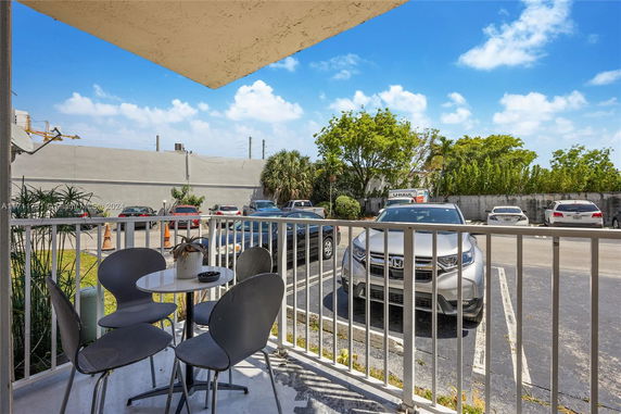 View of a parking area with several parked cars next to a building.