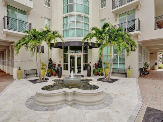 Front view of a modern building entrance with glass windows and a fountain.