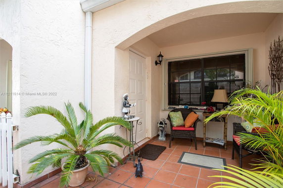 Front entrance of a house with a small covered porch and seating area.