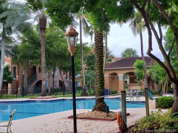 Outdoor swimming pool with surrounding trees and a small building.