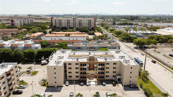 Aerial view of a multi-story residential building with surrounding streets and other buildings.