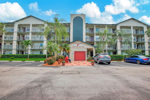 Front view of a multi-story residential building with balconies and parking area.