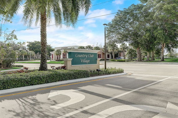 View of the entrance area of Country Club Village with surrounding trees and signpost.