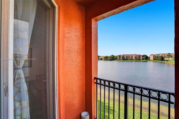 View from a balcony overlooking a body of water with distant buildings.
