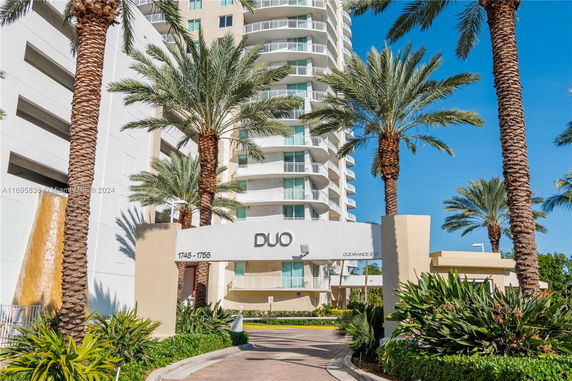 Front view of a tall residential building with balconies and an entrance archway labeled 'DUO'.