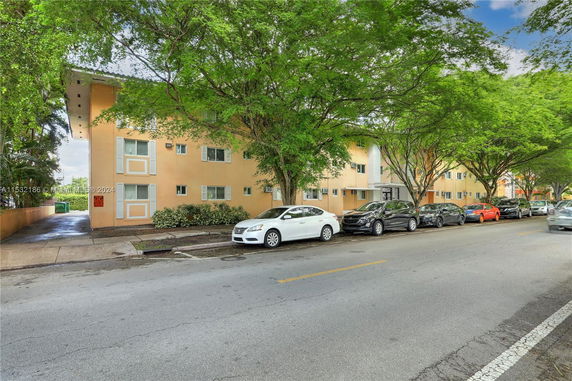 Front view of a multi-story apartment building with parking on the street.