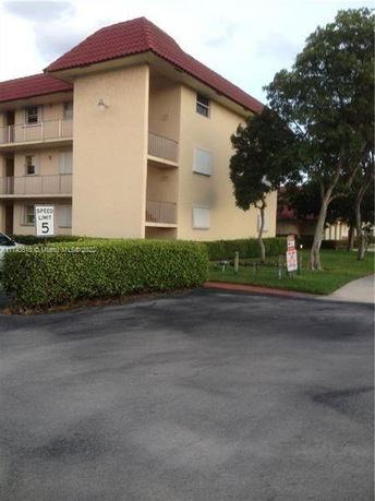 Front view of a multi-story residential building with a red roof.
