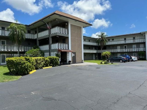 Front view of a multi-story residential building with balconies and parking area.