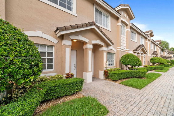 Front view of a row of townhouses with tan exterior and white trim.