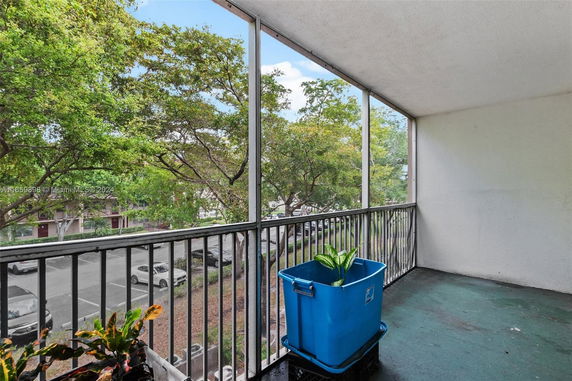 A balcony view with trees and a parking area visible below.