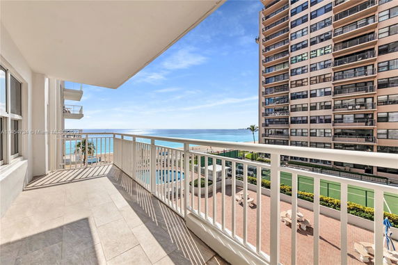 Balcony view of ocean and adjacent tall building near the beachfront.