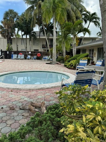 Outdoor swimming pool area surrounded by palm trees and lounge chairs.