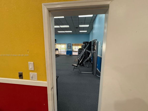View of a gym area with exercise equipment inside a building.